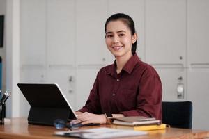 Portrait of attractive entrepreneur asian woman, business woman looking at camera while working for accounting finance with laptop computer. photo