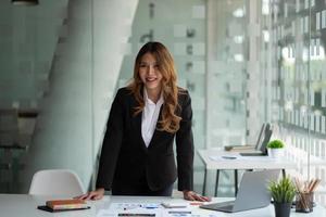 retrato de una atractiva mujer de negocios asiática que trabaja en una laptop para un plan de marketing con papeleo foto