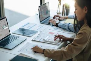 mano de contadora empresaria trabajando en la calculadora para calcular el informe de datos financieros, el documento de contabilidad y la computadora portátil en la oficina, el concepto de negocio foto