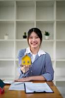 Portrait woman holding house model in hand caontract agreement to buying property. photo