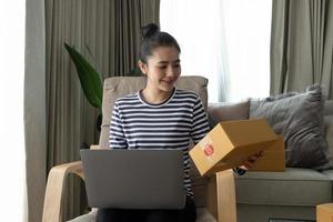 Business Start up SME concept. Young startup entrepreneur small business owner working at home, packaging and delivery situation. Women, owener of small business packing product in boxes photo