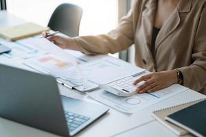 Close up woman planning budget, using calculator and laptop, reading documents, young female checking finances, counting bills or taxes, online banking services photo