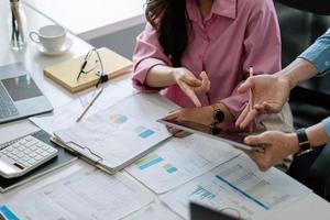 Close up business adviser partnership coworkers using a tablet to chart company financial statements report and profits work progress and planning in office room photo