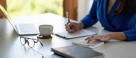 accounting is recording the company's financial growth statistics using calculator for reviewing and analyzing the results, Taking notes and analyzing data graphs in office. photo