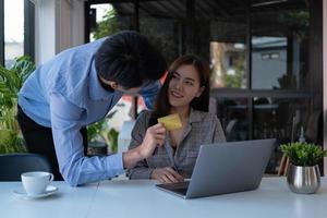 Asian couple at home shopping online with laptop and credit card photo