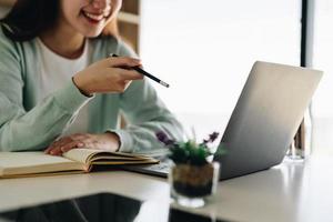 Concentrate asian gial freelancer wearing headset, communicating with client via video computer call. Millennial pleasant professional female tutor giving online language class. photo