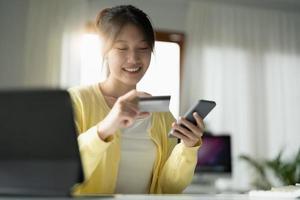 Close up of girl hold bank credit card, shopping online using mobile phone, buying goods or ordering online, entering bank accounts and details in online banking offer. photo