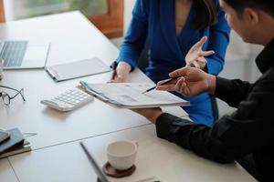 Two colleagues discussing data with document data on desk table. Close up business people meeting to discuss the situation on the market. photo