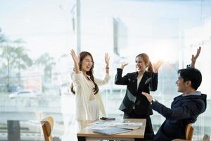 Young multiethnic diverse creative asian group huddle and high five hands together in office workshop with success or empower expression in teamwork. Young asian marketing team with copy space photo