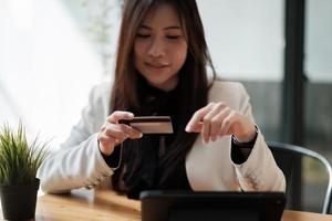 mujer joven con tarjeta de crédito y usando un teléfono inteligente para comprar en línea. concepto de compra de pago en línea. banner de espacio de copia foto