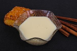 Condenced milk in the bowl with sinnamon and pastry photo