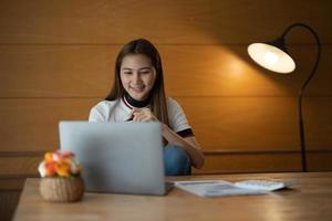 mujer de negocios analista contable documentos mirando la pantalla de la computadora portátil haciendo investigación tecnológica del mercado comercial en línea pensando en trabajar sentada en el escritorio de la oficina en casa foto