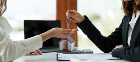 real estate agent holding house key to his client after signing contract agreement in office,concept for real estate, moving home or renting property photo