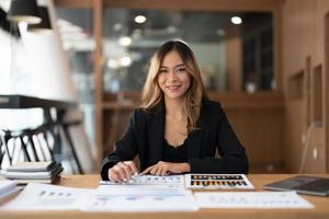 Portrair accountant asian woman working and analyzing financial reports project accounting with chart graph and calculator in modern office  finance and business concept. photo