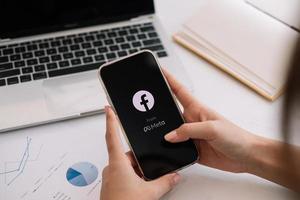 Woman holds iPhone 13 with facebook application logo on the screen. facebook is a photo-sharing app for smartphones. photo