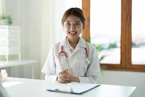 retrato de una doctora sonriente con estetoscopio sentada en la clínica foto