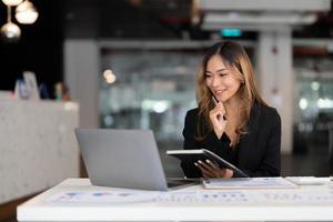 mujer asiática de negocios joven que trabaja en una computadora portátil en la oficina para el concepto financiero de contabilidad foto