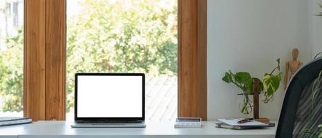 Blank screen laptop computer in minimal office room with calculatpr and decorations and copy space. photo
