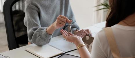 Agente de bienes raíces que tiene la llave de la casa para su cliente después de firmar un contrato en la oficina, concepto de bienes raíces, mudanza o alquiler de propiedad. foto