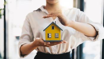 Concept home insurance, protection from burglary or destruction. Woman with her hands covers the houses of red color with the heart inside. photo