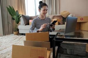 Young asian woman entrepreneur, teenager is work at home business owner by computer in morning. Happy woman is smilling for her work. SME work at home concept photo