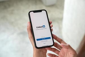 una mujer sostiene un apple iphone 13 pro max con la aplicación linkedin en la pantalla.linkedin es una aplicación para compartir fotos para teléfonos inteligentes