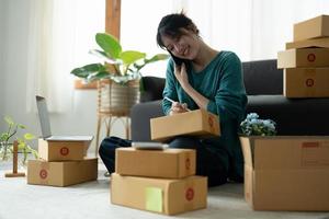 business owner writing address on cardboard box at workplace. freelance woman seller prepare parcel box of product for deliver to customer. Online selling, e-commerce, shipping concept