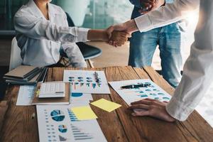 Group business people handshake at meeting table in office together. Young businessman and businesswoman workers express agreement of investment deal. photo