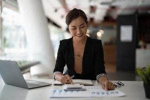 mujer contadora empleada presione a mano en la calculadora para hacer un informe financiero o las ganancias mensuales de la empresa en el escritorio, el trabajo de contador y el concepto de trabajo desde casa foto