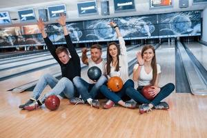 That was good game. Young cheerful friends have fun in bowling club at their weekends photo