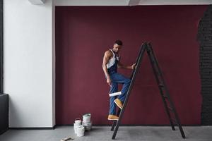 hagámoslo. joven trabajador afroamericano con uniforme azul tiene trabajo que hacer foto