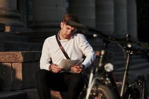 Clarifying data in the document. Businessman in formal clothes with black bicycle is in the city photo