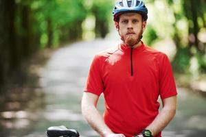 Ready and prepared. Cyclist on a bike is on the asphalt road in the forest at sunny day photo