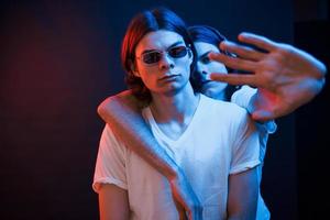 Don't touch my brother. Portrait of twins. Studio shot in dark studio with neon light photo