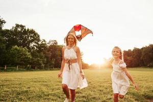 Unity of people. Mother and daughter have fun with kite in the field. Beautiful nature photo
