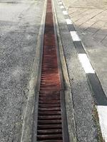 water drain or ditch on the road. Gutters drain grate, drain cover. Road drains - sewer cover. iron grate of water drain on the road in every city. Water go down to the drain on the road photo