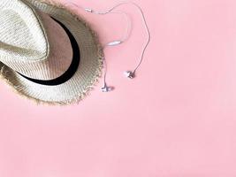 Woven hat and white ear phone on pastel pink color background summer photo