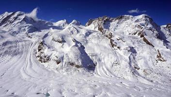 montañas de los alpes nevados y nubes de cielo azul foto