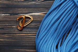 This should be enough for high hills. Isolated photo of climbing equipment. Part of carabiner lying on the wooden table