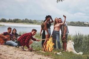 Come on, let's make photo. Group of people have picnic on the beach. Friends have fun at weekend time photo