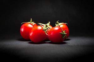 Red cherry tomatoes isolated on black photo