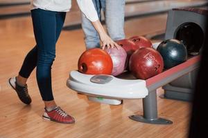 tomando una pelota. vista recortada de la gente en el club de bolos lista para divertirse foto