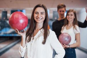 Toothy smile. Young cheerful friends have fun in bowling club at their weekends photo