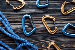 In random order. Isolated photo of climbing equipment. Part of carabiner lying on the wooden table