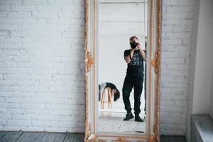 Man with camera taking a shot in the vintage mirror. Girl is having fun behind photo