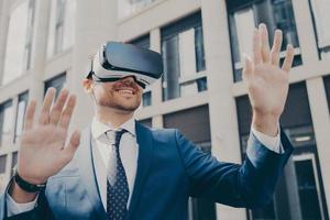 Professional impressed worker standing outside alone and using VR glasses to visualize projects photo