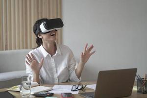 Business lady wears VR headset for laptop raising hands up as trying to touch objects in 3D reality photo