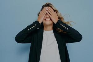 Funny blond beautiful female closing eyes with her hands, having fun and playing hide and seek photo