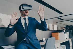 CEO man in VR headset interacting with virtual objects or interface while sitting in office photo