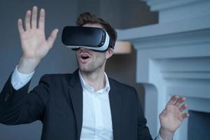 Man entrepreneur in formal suit sitting at home office while testing VR goggles photo
